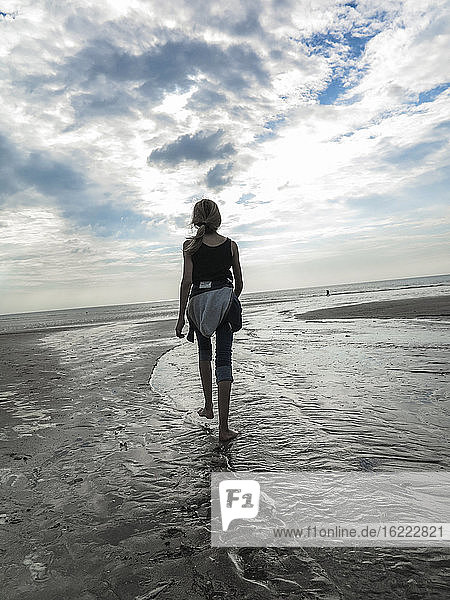 Young girl seen from behind walking on a beach
