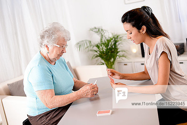 cheerful young girl playing cards with elderly senior woman