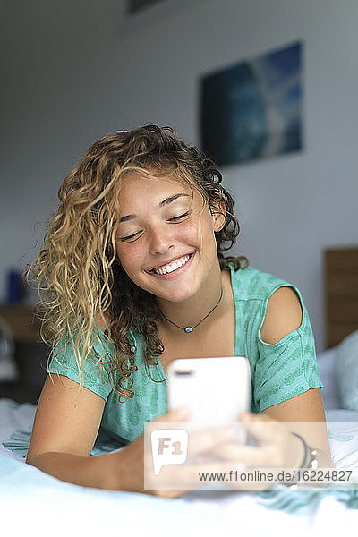 Junger Teenager zu Hause mit einem Smartphone