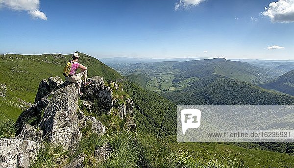 Hiker overlooking Cantal mountains  Auvergne Volcanoes Regional Natural Park  Cantal department  Auvergne-Rhone-Alpes  France  Europe