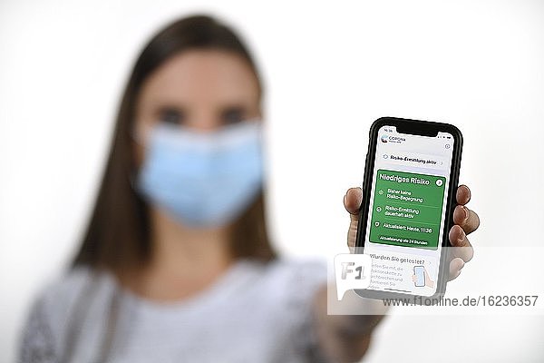 Frau mit Mundschutzmaske  zeigt Smartphone mit Corona Warn-APP im grünen Bereich  Corona-Krise  Baden-Württemberg  Deutschland  Europa