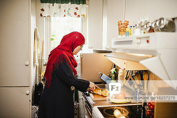 Frau in Küche schneidet Orangen
