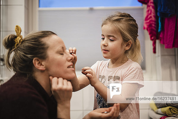 Girl putting make-up on mothers face