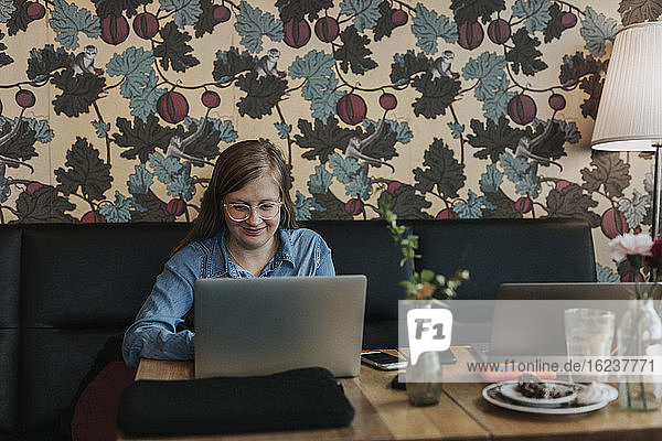 Lächelnde Frau mit Laptop in einem Café