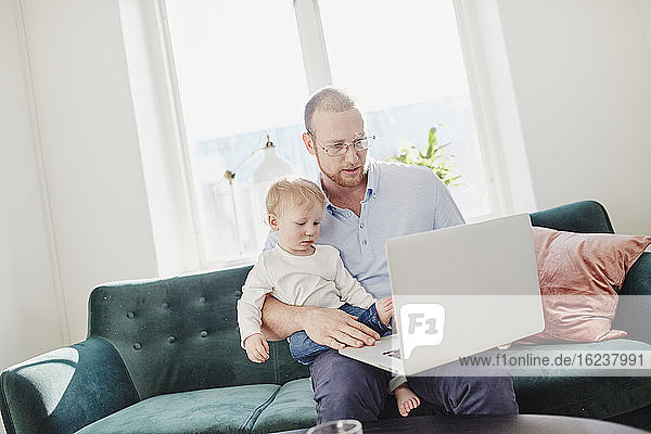 Father and toddler son using laptop