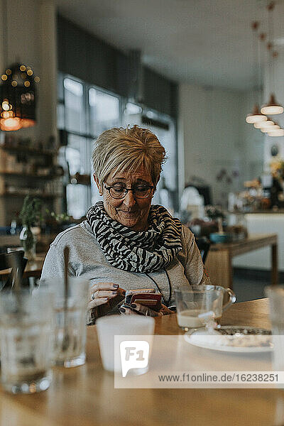 Ältere Frau telefoniert im Cafe