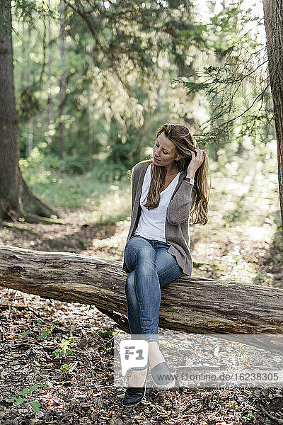 Woman sitting on log in forest