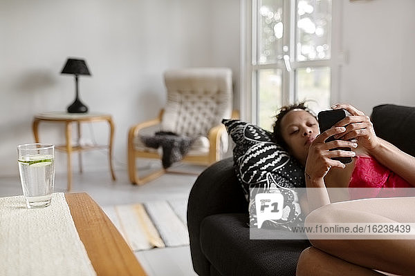Frau auf Sofa mit Mobiltelefon