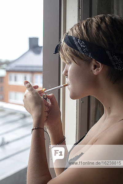 Frau raucht Zigarette am Fenster