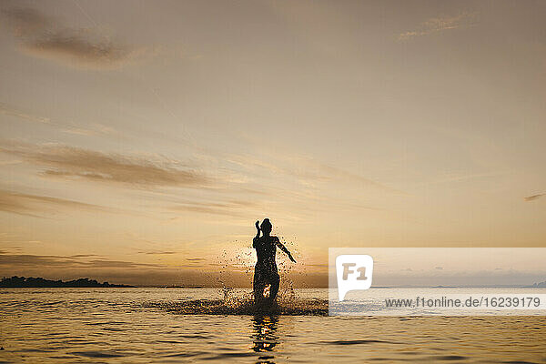 Frau beim Baden im Meer bei Sonnenuntergang