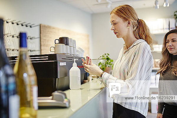 Woman in cafe applying hand sanitizer