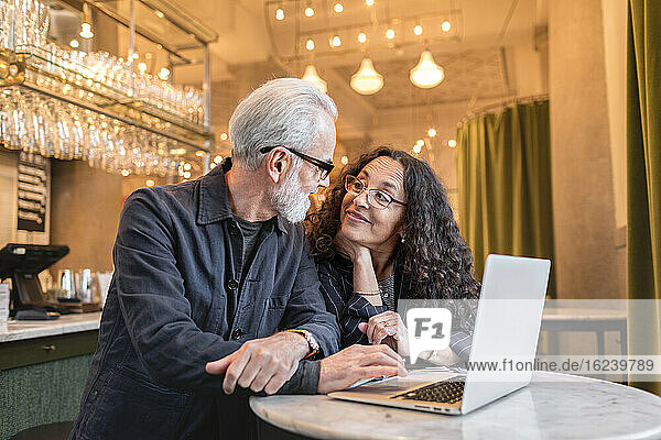Mature couple using laptop in cafe
