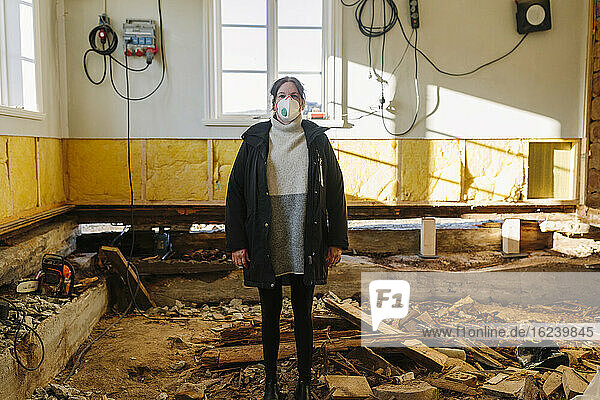 Frau mit Schutzmaske in zerstörtem Gebäude
