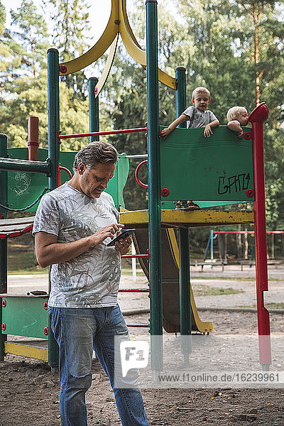 Vater mit Kindern auf dem Spielplatz