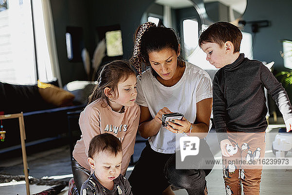 Mutter mit Kindern schaut auf ihr Handy