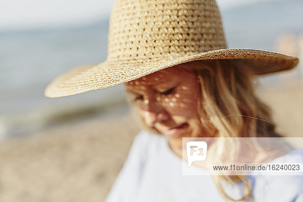 Frau mit Strohhut am Strand