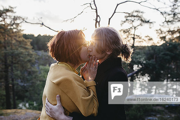 Female couple kissing at sunset