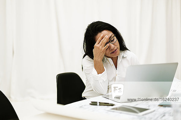 Müde Geschäftsfrau mit Laptop bei der Arbeit
