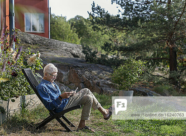 Man in garden reading newspaper