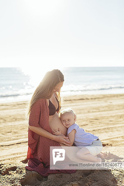 Schwangere Frau mit Tochter am Strand