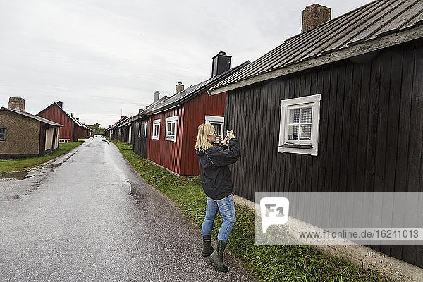 Woman taking photo of wooden house