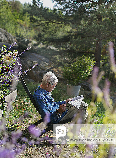 Mann im Garten liest Zeitung