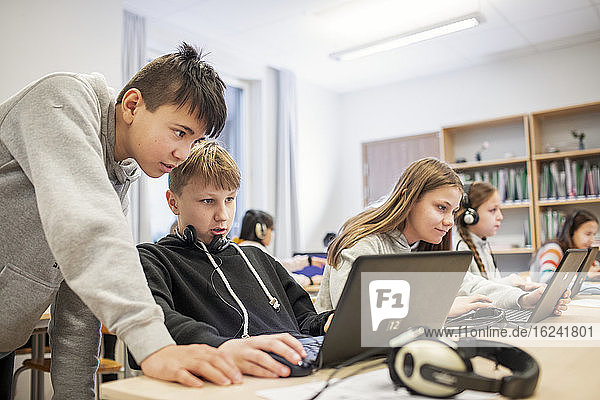 Boys in classroom using laptop