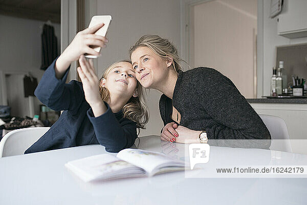 Mutter und Tochter machen Selfie bei den Hausaufgaben