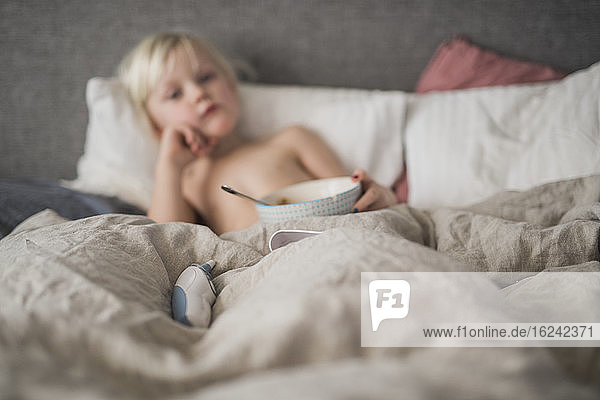 Digitales Thermometer auf dem Bett  Junge im Hintergrund