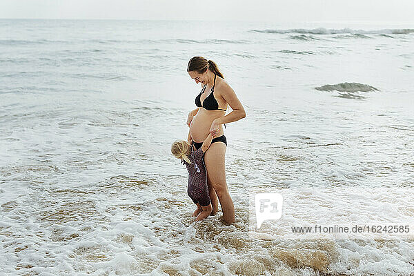 Pregnant woman with daughter at sea