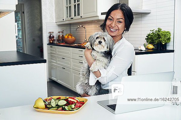 Lächelnde Frau in der Küche mit Hund