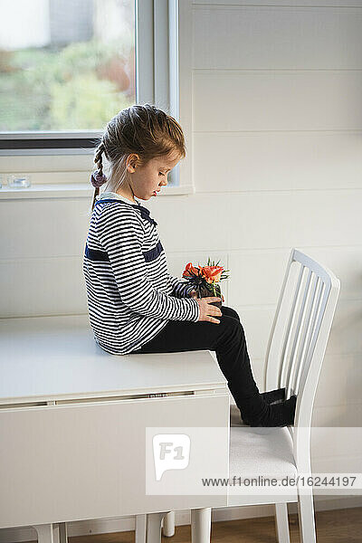 Mädchen sitzt auf einem Tisch mit Blumen