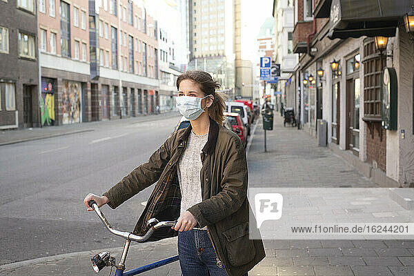 Frau mit Fahrrad und Gesichtsmaske
