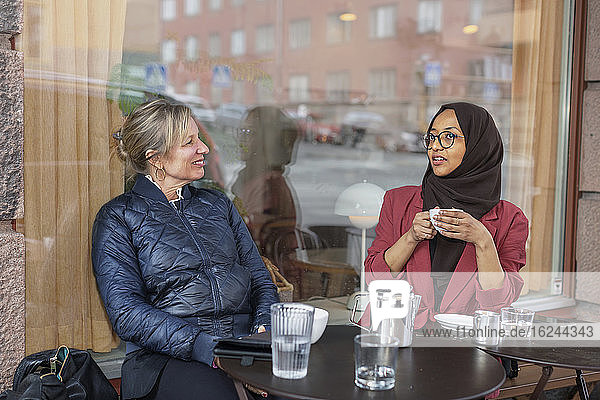 Weibliche Freunde trinken Kaffee in einem Straßencafé