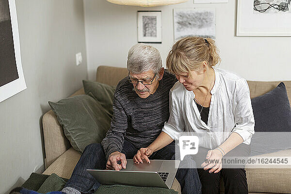 Couple using laptop on sofa