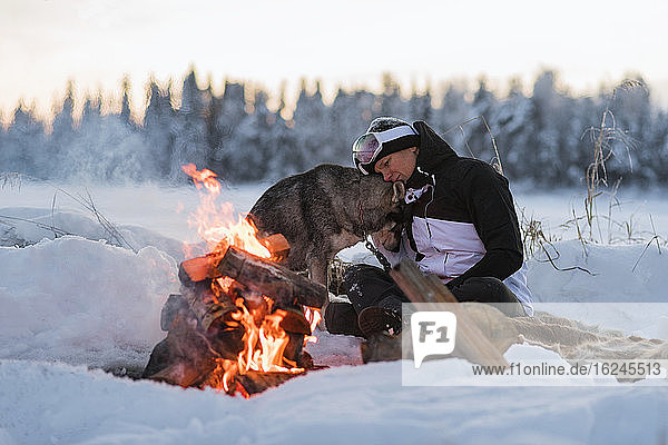 Woman with dog sitting at camp fire
