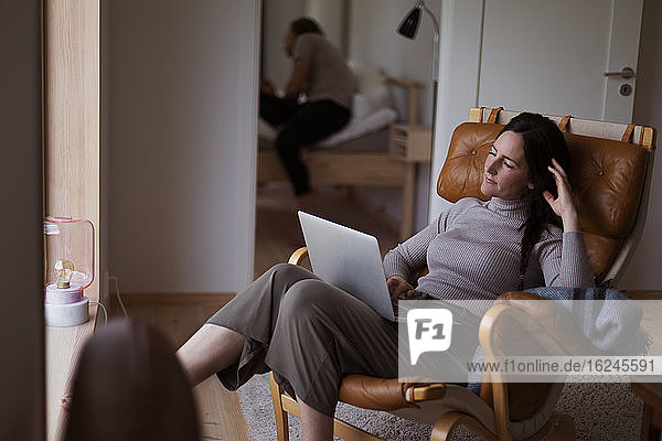 Frau auf Sessel sitzend mit Laptop