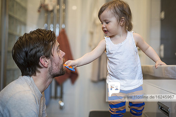 Mädchen putzt Vätern die Zähne