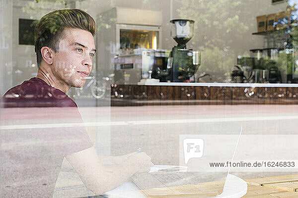 Mann im Café schaut durch das Fenster