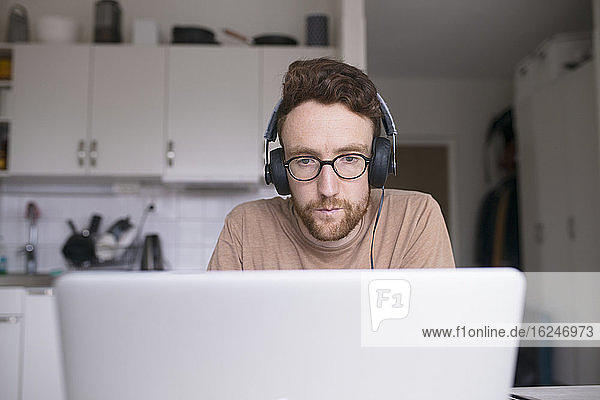 Mann arbeitet zu Hause am Laptop