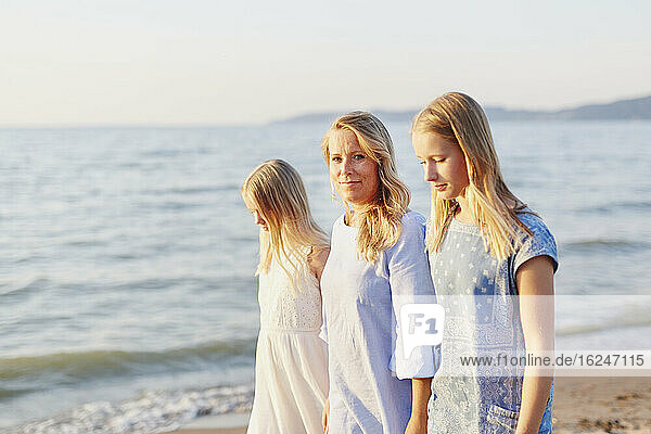 Mother with daughters walking on beach