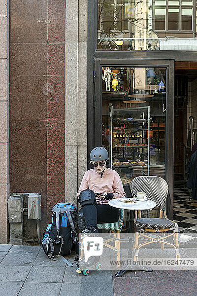 Weibliche Skaterin in einem Straßencafé