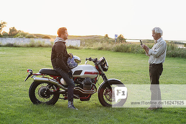 Vater fotografiert erwachsenen Sohn auf Motorrad
