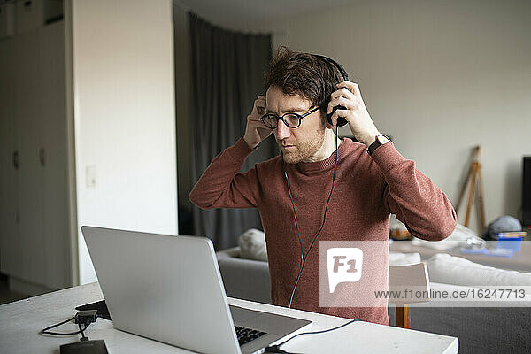 Mann mit Kopfhörern und Laptop