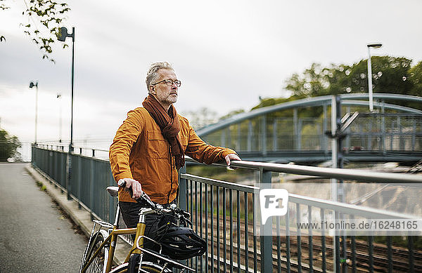 Mann mit Fahrrad auf Brücke stehend