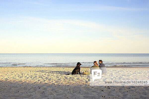 Ehepaar mit Hund entspannt sich am Strand