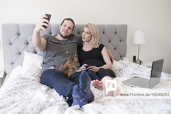 Paar auf dem Bett nimmt Selfie