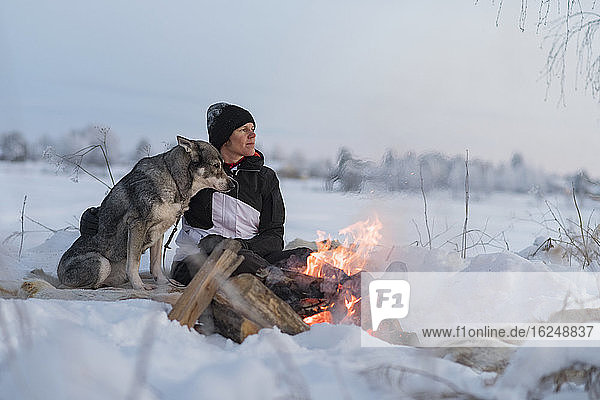 Woman with dog sitting at camp fire