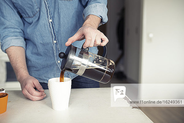 Mann gießt Kaffee aus französischer Presse