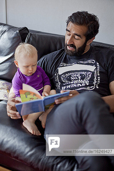 Vater liest seinem kleinen Mädchen ein Buch vor